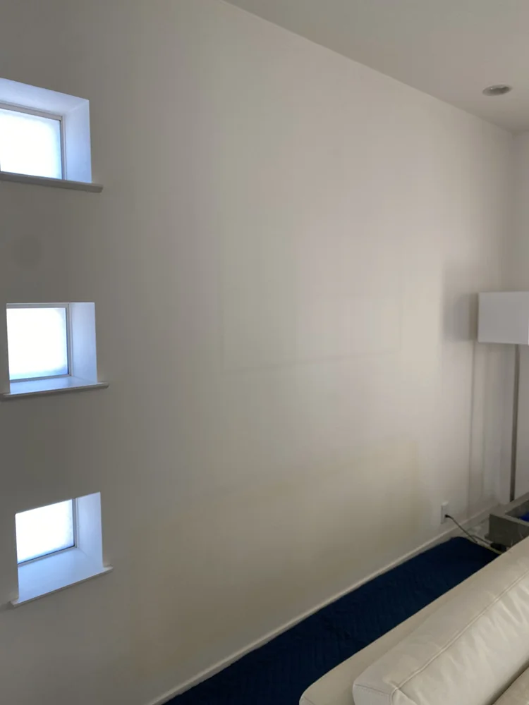 まずはソファ等を移動し、 床にキルティングを敷いて作業スペースを確保。 ミラーを実際に壁にあて、お客様に位置を決めて頂く。